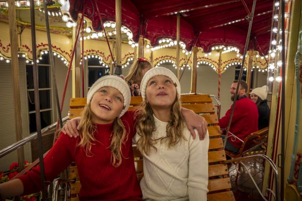 Two young girls on bench on carousel