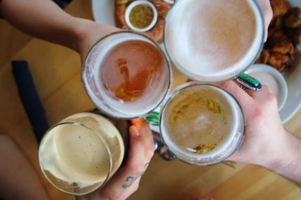 4 patrons holding their beer up in a toast at a brewery in Salt Lake City