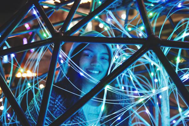A festival goer smiles from within an interactive light exhibit.