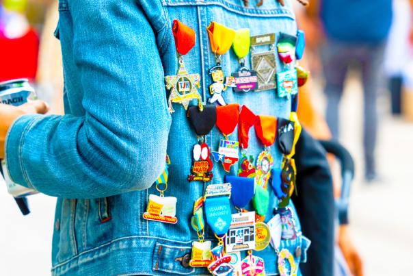 Back of person wearing jean jacket filled with Fiesta medals.