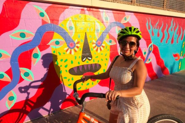 Girl with bike helmet on bike in front of mural