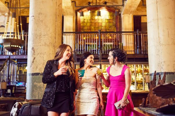 Three girls enjoying drinks in beautiful room with two large pillars