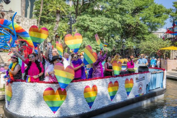 River barge with rainbow hearts and people floating on River Walk