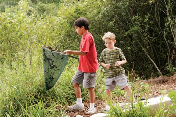 Two boys, one holding a net, on a walking trail surrounded by greenery in Sandy Springs, GA