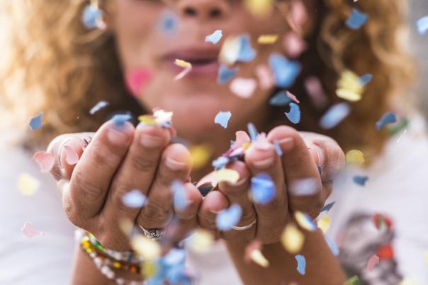Woman Blowing Colorful Confetti Out Of Her Hands At The Camera