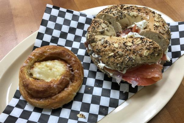 A Danish and bagel sitting on checkered paper on a plate at City Bagel Cafe in Sandy Springs.