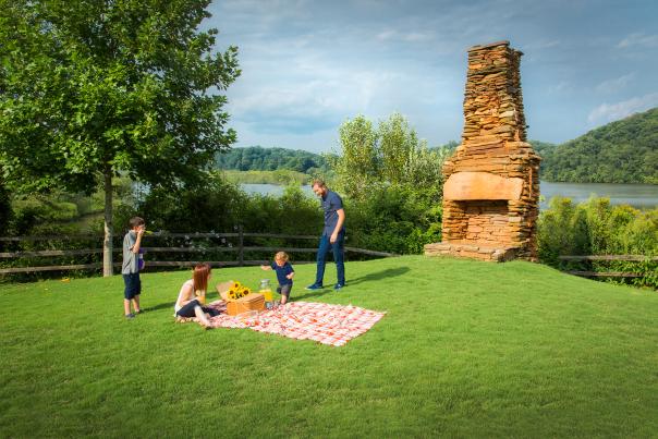 A family setting up for a picnic on the grass at Morgan Falls Overlook Park in Sandy Springs, Georgia over by the fireplace.