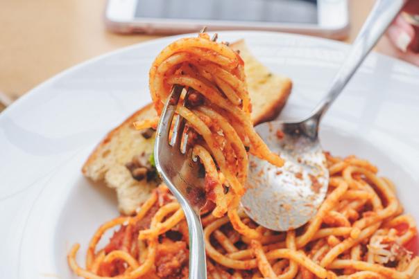 A bowl of pasta in front of a phone