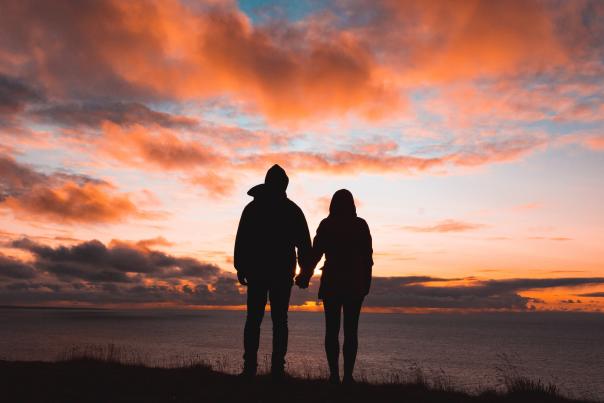 Couple-admiring-the-sunset-while-holding-hands-in-front-of-the-beach