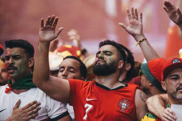 Men wearing red and white jerseys watching intense soccer game.