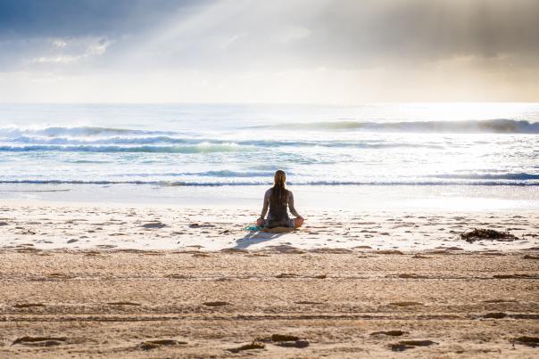 Woman relaxing at the beach practicing meditation