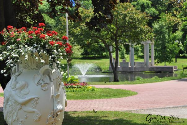 Large urn of flowers in Congress Park with fountain behind it