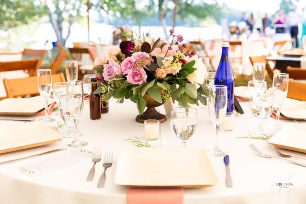 PS Events table setting with floral centerpiece, champagne glasses and blue Saratoga Water bottle.