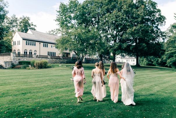 Bride and bridal party walking up back lawn toward the building