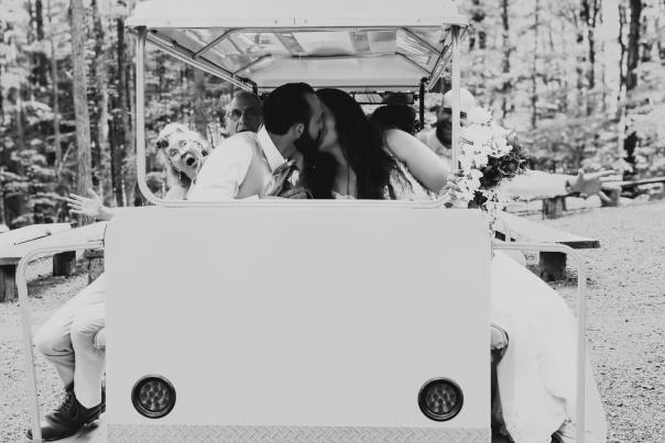 black and white photo of bride and groom kissing in cart
