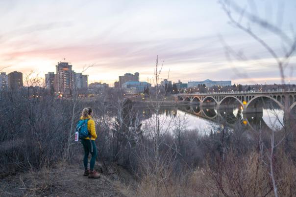 A hiker looks at the Saskatoon, SK skyline at sunset
