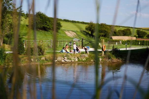 peering through some reeds at campers on the other side of a riverbank