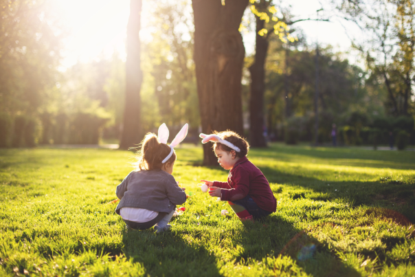 Two girls with bunny headbands on searching for easter eggs in a field