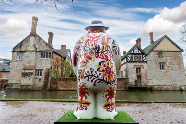 The rear view of a painted snowman statue facing the moat and Baddesley Clinton