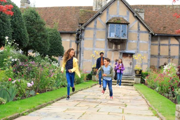 Two children and their parents running along a garden path in front of Shakespeare's Birthplace