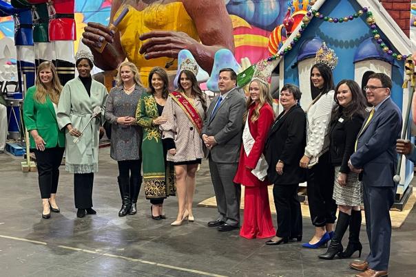 Grouping of Louisiana Travel Association, Louisiana Office of Tourism and CVB representatives with pageant queens, Mardi Gras floats in background