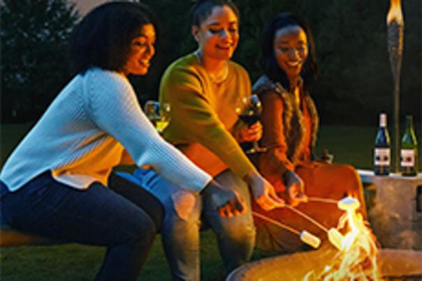 Three young women roasting marshmallows over a campfire