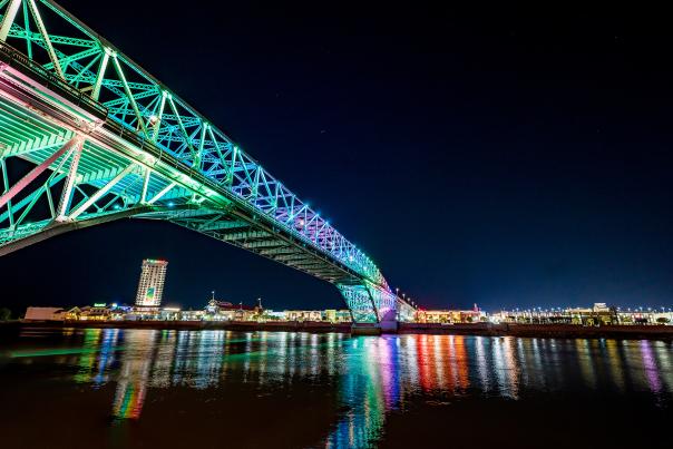 LED-lit Bakowski Bridge of Lights on the Texas Street Bridge over the Red River in the foreground, Bossier City skyline against a night sky in background