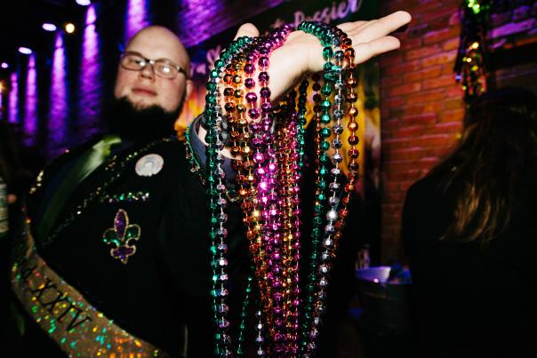 of man holding Mardi Gras beads