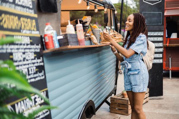 Woman in a denim outfit getting fries from a food truck.