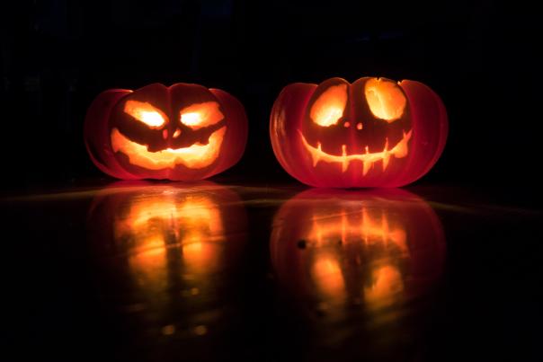 two jack-o-lanterns sit side by side glowing from the lit candle inside