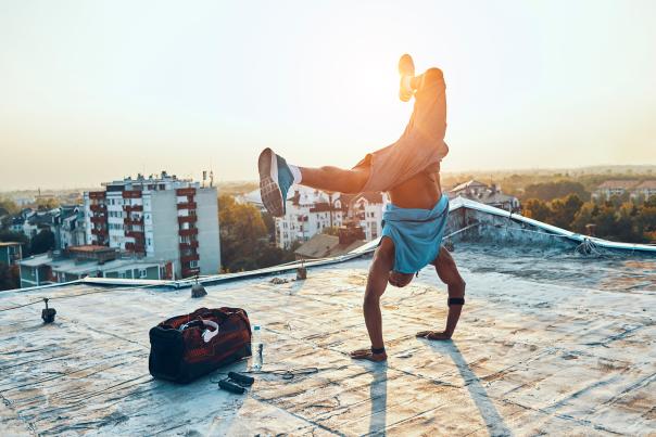 A man in a handstand breakdances on a roof.