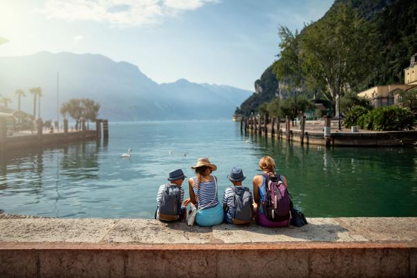 Family enjoying Garda Lake vacations. They are sitting in harbor of Riva del Garda and enjoying view of Lake Garda.