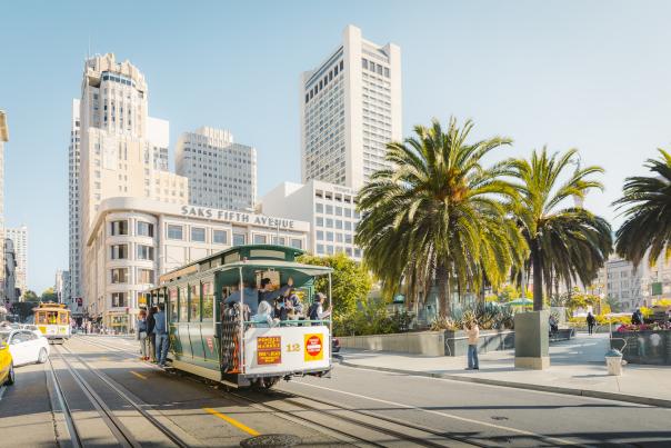 A trolley goes up the street near Union Square on a sunny San Francisco day.