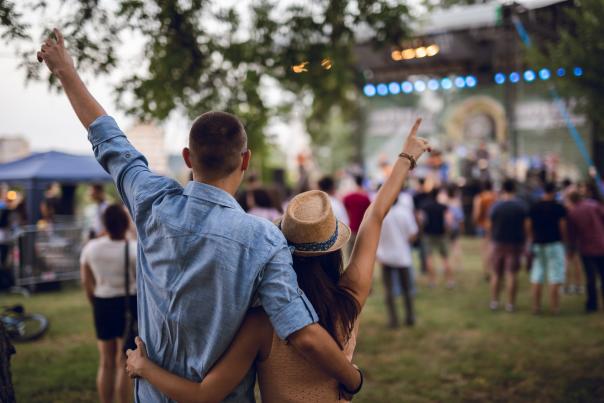 A couple with arms around one another watches a live concert performance.