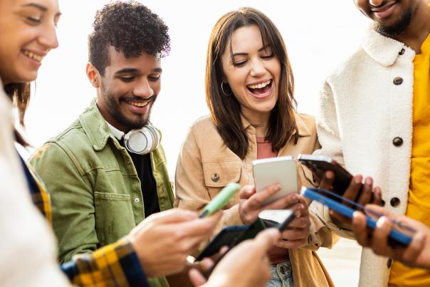 A happy group of young friends using smartphones on the street