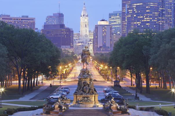 A statue in the forefront of a road in downtown Philadelphia.