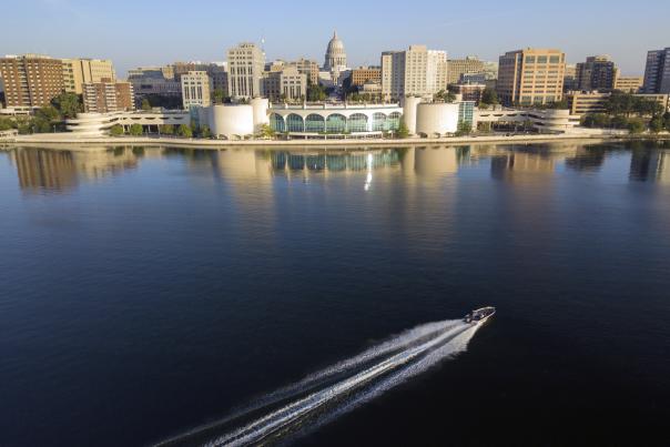 A boat cruises in front of the Madison, WI skyline on Lake Monona
