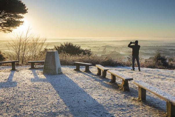 Man looks into the far horizon at the sunrise on a frosty morning from the top of Surrey's Leith Hill