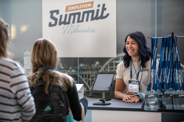A woman greets guests at the registration desk for Simpleview Summit 2024 in Milwaukee.
