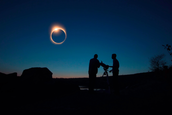 Two men set up a telescope to watch an eclipse