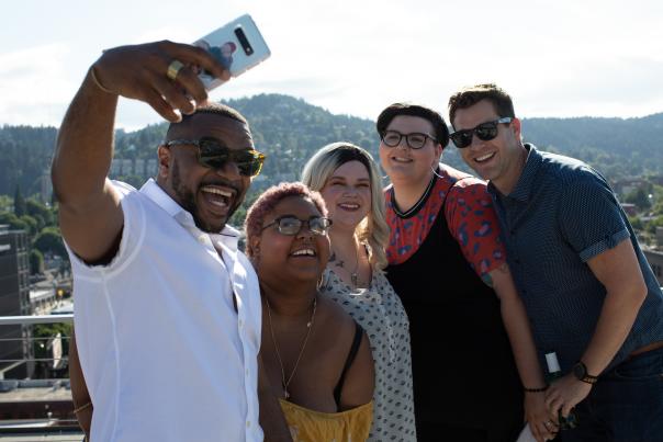 Five diverse friends take a selfie on a rooftop