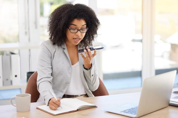 An event planner talks on the phone while taking notes in a notebook.