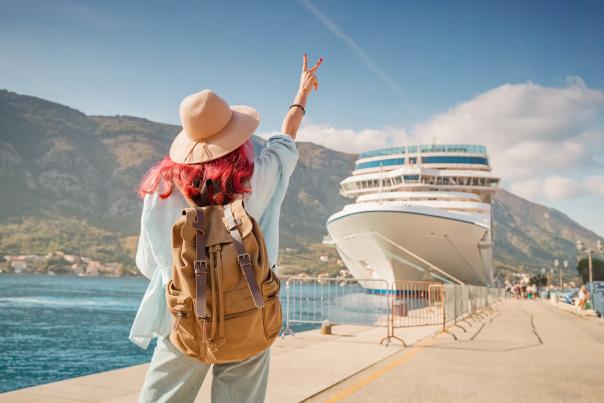 A person gesturing towards a cruise ship that is docked.