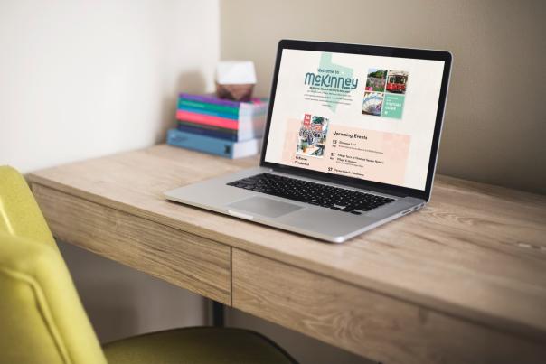 The Visit McKinney homepage open on a laptop that's sitting on top of a desk.