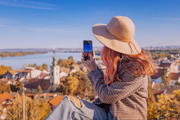 Traveler capturing photos of a historic city and waterfront with a mobile phone.