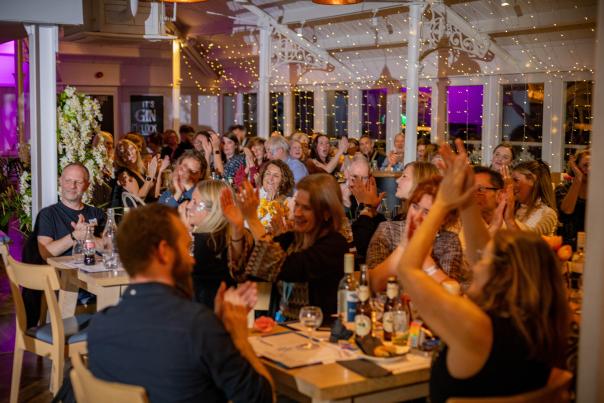 Attendees of EMEA Summit sit at tables with a variety of drinks and cheer on award winners.