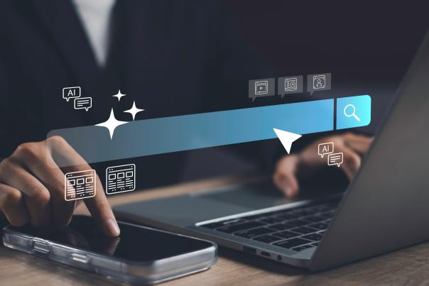 A person working on a laptop computer and mobile phone with a search bar and AI-themed icons overlaid.