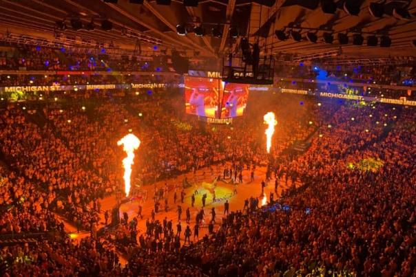 Pyro shoots off before a game inside of a sports arena.