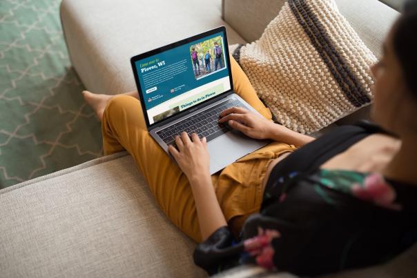 A person sitting on a couch with a laptop open to the Plover CVB website.