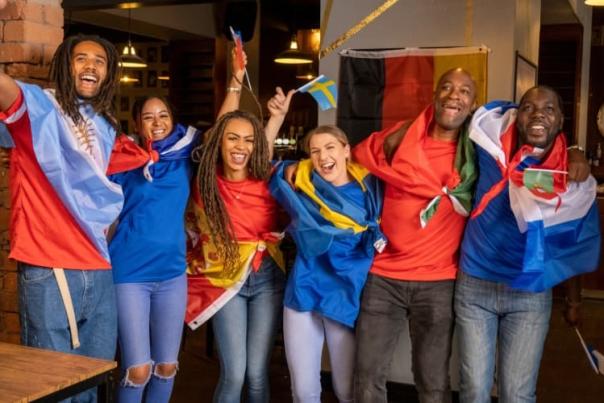 Group of fans draped in international flags celebrating together, symbolizing the global excitement and travel opportunities around the World Cup.